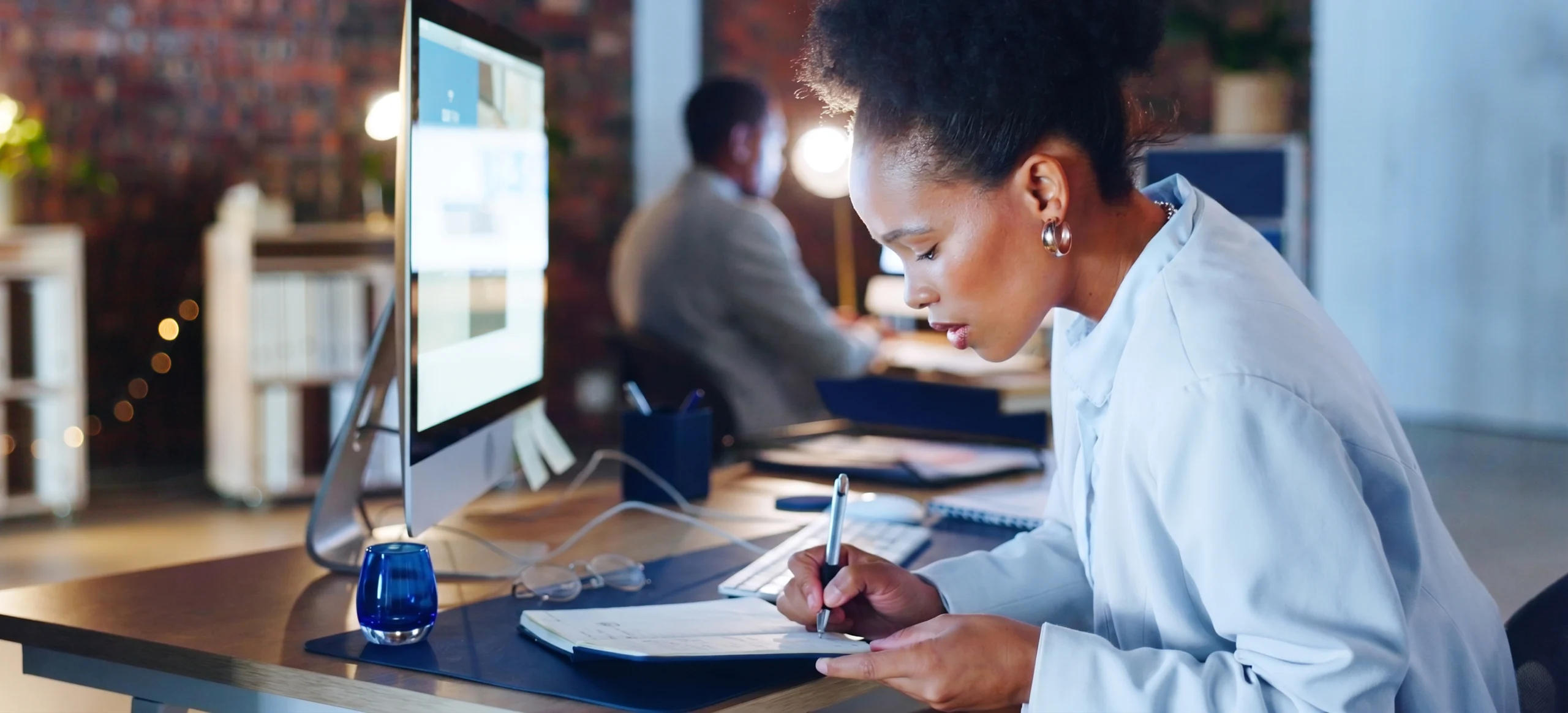 A dealership owner writes down which blogs she plans to update at her desk.